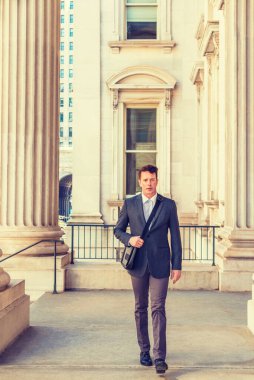 New York 'ta çalışan Amerikalı iş adamı, çizgili ceket, beyaz atlet, pantolon, deri ayakkabı, siyah omuz çantası taşıyan, klasik ofis binasında yürüyen, işe giden.