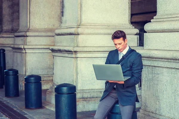 Amerikalı iş adamı seyahat ediyor, New York 'ta çalışıyor, çizgili ceket giyiyor, omuz çantası taşıyor, sokak sütununda oturuyor, aşağı bakıyor, okuyor, dizüstü bilgisayarla çalışıyor.. 