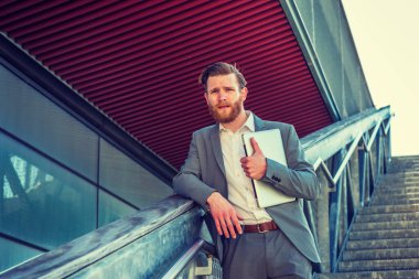 Başarının yolu. New York 'ta sakallı, bıyıklı, mavi takım elbiseli, beyaz tişörtlü, dizüstü bilgisayarlı, kampüste merdivenlerde bekleyen,.