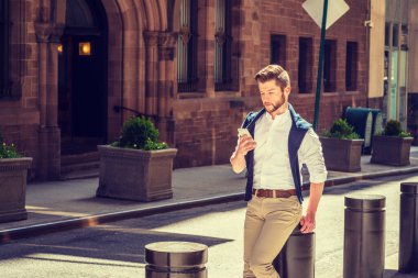 New York 'ta güneşli bir bahar tatili. Sakallı, beyaz tişörtlü, kahverengi pantolonlu, omzuna mavi kazak takılmış, klasik binalı sokakta oturan, okuyan, cep telefonuyla mesajlaşan Amerikalı bir adam..