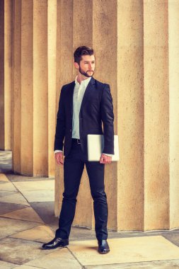 New York 'ta çalışan sakallı Amerikalı bir işadamı, siyah takım elbise, beyaz gömlek, deri ayakkabılar, kolunda dizüstü bilgisayar, ofisin dışında bekliyor., 