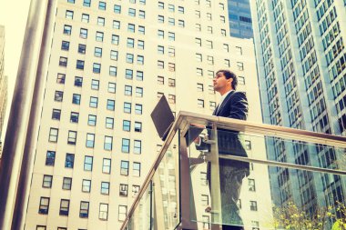 Big City 'de büyüme. Doğu Hintli Amerikalı öğrenci, New York 'ta okuyor, siyah takım elbise giyiyor, iş bölgesinde parmaklıklar arkasında duruyor, dizüstü bilgisayarla çalışıyor, yukarı bakıyor, düşünüyor,. 