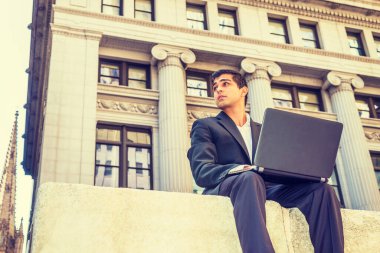 Modern Teknolojinin Gücü. Doğu Hintli Amerikalı üniversite öğrencisi seyahat ediyor, New York 'ta okuyor, ofis binasının dışındaki sokakta oturuyor, dizüstü bilgisayarla çalışıyor.. 