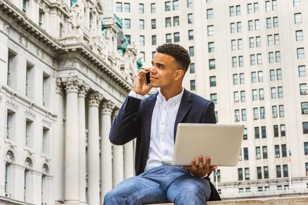 Modern hayat. New York 'ta okuyan Afrikalı Amerikalı üniversite öğrencisi, caddedeki klasik ofis binasında oturuyor, okuyor, dizüstü bilgisayarda çalışıyor, cep telefonuyla konuşuyor.. 