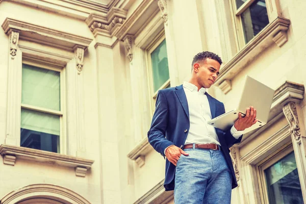 Başarının yolu. New York 'ta okuyan Afro-Amerikan üniversite öğrencisi, mavi ceketli, beyaz gömlekli, klasik ofis binasının önünde duran, dizüstü bilgisayarla çalışan. 