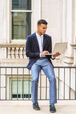 Afrikalı Amerikalı üniversite öğrencisi New York 'ta okuyor. Mavi ceketli, gri pantolonlu, spor ayakkabılı, kampüsteki klasik ofis binasının korkuluklarında oturan, okuyan, dizüstü bilgisayarda çalışan bir genç...