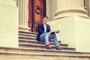 Afrikalı Amerikalı üniversite öğrencisi New York 'ta okuyor. Ceketi, gri pantolonu, kırmızı çorapları, spor ayakkabıları var. Adam ofis binasının merdivenlerinde oturuyor. Dizüstü bilgisayarında çalışıyor, gülümsüyor..