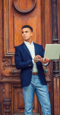 Afrikalı Amerikalı üniversite öğrencisi New York 'ta okuyor. Koyu mavi ceket giyen, kampüsün klasik ofis kapısında duran, dizüstü bilgisayarla çalışan, kafasını kaldırıp,. 