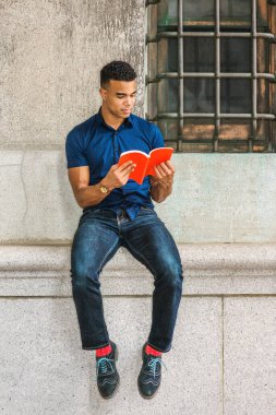 Afrikalı Amerikan Koleji öğrencisi New York 'ta okuyor. Mavi kısa kollu gömlek, kot pantolon, kırmızı çorap, spor ayakkabı giyen genç adam sokakta klasik duvara yaslanmış, kırmızı kitap okuyor.. 