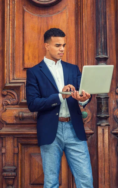 Afrikalı Amerikalı üniversite öğrencisi New York 'ta okuyor. Koyu mavi ceket giyen genç adam, kampüsün klasik ofis kapısında duruyor, okuyor, dizüstü bilgisayarla çalışıyor..