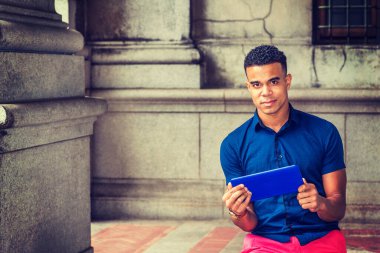 Okumayı seviyorum. Modern okuma. Mavi kısa kollu gömlekli Afro-Amerikalı bir adam, New York 'ta klasik caddede oturuyor, küçük mavi tablet bilgisayar okuyor, kafasını kaldırıp düşünüyor,. 