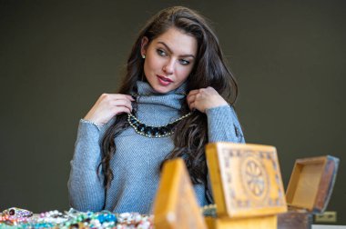 Aynada farklı takıları seçen ve deneyen bir kadının yansıması, yumuşak odak, yakın plan