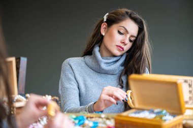 Aynada farklı takıları seçen ve deneyen bir kadının yansıması, yumuşak odak, yakın plan