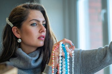 Aynada farklı takıları seçen ve deneyen bir kadının yansıması, yumuşak odak, yakın plan