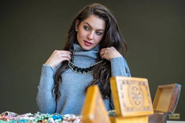 Aynada farklı takıları seçen ve deneyen bir kadının yansıması, yumuşak odak, yakın plan