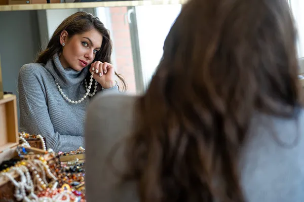 Aynada farklı takıları seçen ve deneyen bir kadının yansıması, yumuşak odak, yakın plan