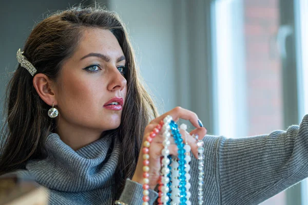 Aynada farklı takıları seçen ve deneyen bir kadının yansıması, yumuşak odak, yakın plan