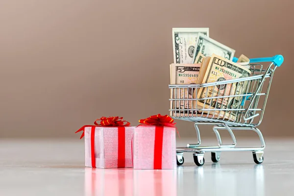 圣诞开支计划概念 礼品盒及装满现金的购物车 — 图库照片