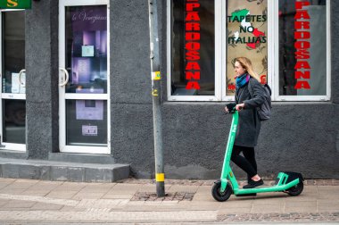 Riga, Letonya, 2 Kasım 2021, yaya geçidinde elektrikli scooter kullanan genç bir kadın.