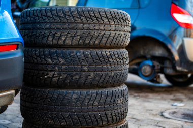 Kış lastikleri tekerlek servisindeki arabanın yanında mevsimlik lastik değiştirme konsepti, yakın çekim.