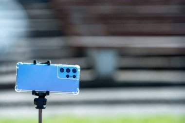 Riga, Letonya - 01 Mayıs 2021: teleskopik bir tripodun üzerinde birkaç kameralı modern akıllı telefon, uzaktan kumanda ve tripod kullanarak selfie