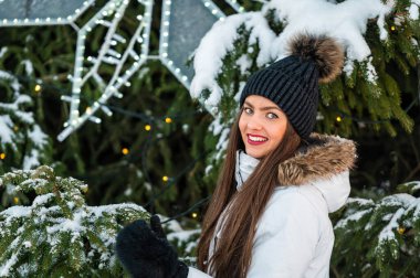 Noel ağacının arka planında çok güzel genç bir kadının açık hava portresi.