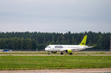 Riga, Letonya - 31 Ağustos 2021: AirBaltic Airbus A220-300 YL-AAS bulutlu bir sonbahar gününde RIX Uluslararası Havaalanından havalandı
