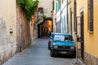 Pisa, İtalya - 9 Ağustos 2021: Eski şehrin dar bir sokağında bir sıra araba