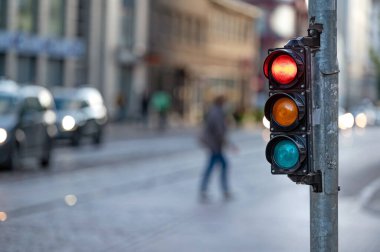Trafik ışıklarıyla şehir trafiğinin bulanık görüntüsü, ön planda kırmızı ışıklı bir semafor.