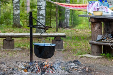 Ormandaki kamp ateşinde yemek pişirmek, yemek kampı konsepti kırsal kesimdeki evde şenlik ateşi yakmak.