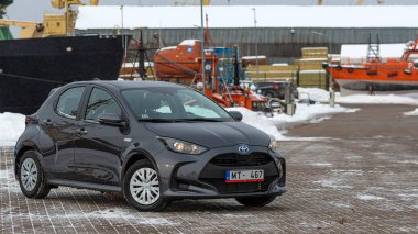 Riga, Letonya - 9 Şubat 2021: Metalik gri Toyota Yaris Hybrid Y20 model araba endüstriyel arka planda
