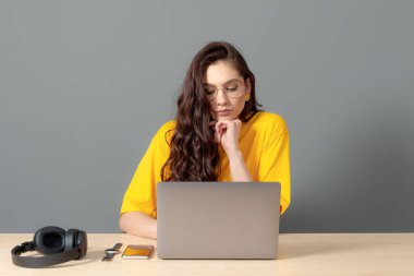 Genç bayan masada oturuyor, çalışırken modern teknolojiyi kullanıyor, online çalışma konsepti