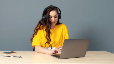 Öğrenci kulaklıkla bilgisayarda oturur ve çevrimiçi video dersleri izleyip dinler.