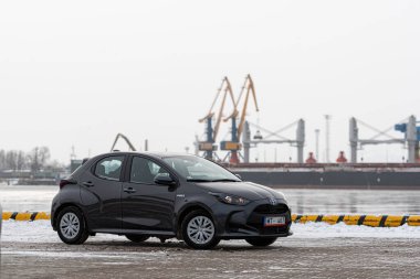 Riga, Letonya - 9 Şubat 2021: Metalik gri Toyota Yaris Hybrid Y20 versiyonu Hatchback arabası deniz kenarına park edilmiş.