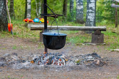 Ormandaki kamp ateşinde yemek pişirmek, yemek kampı konsepti kırsal kesimdeki evde şenlik ateşi yakmak.