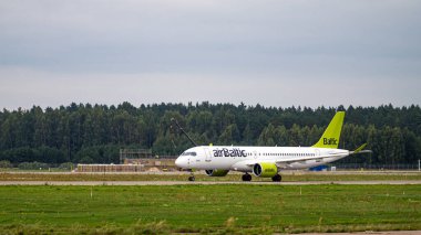 Riga, Letonya - 31 Ağustos 2021: AirBaltic Airbus A220-300 YL-AAS bulutlu bir sonbahar gününde RIX Uluslararası Havaalanından havalandı
