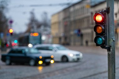 Bulanık arka planda semaforlu bir şehir. Akşam caddelerinde arabalar, kırmızı ışık.