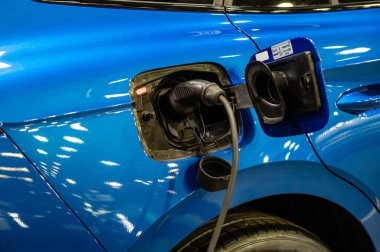 plug of the charging cable plugged into an electric car, charging an electric car at the station