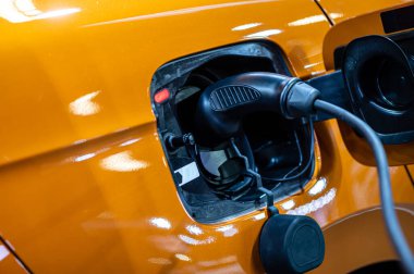 plug of the charging cable plugged into an electric car, charging an electric car at the station