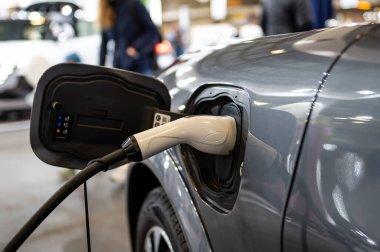 Şarj kablosunun fişi bir elektrikli arabaya takılı, istasyonda bir elektrikli arabayı şarj ediyor.