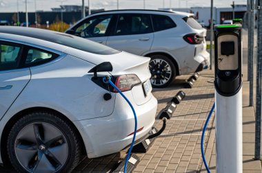 Riga, Letonya, 29 Nisan 2022: Süpermarketteki şarj istasyonundaki elektrikli arabalar Tesla Model S ve BMW ix3