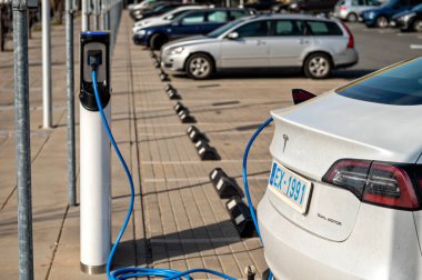 Riga, Letonya, 29 Nisan 2022: elektrikli otomobil Tesla Model S Dual Motor süpermarketin açık otoparkındaki şarj istasyonunda
