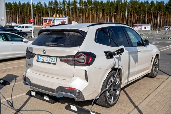 Riga, Letonya, 29 Nisan 2022: Süpermarketteki şarj istasyonundaki elektrikli arabalar Tesla Model S ve BMW ix3