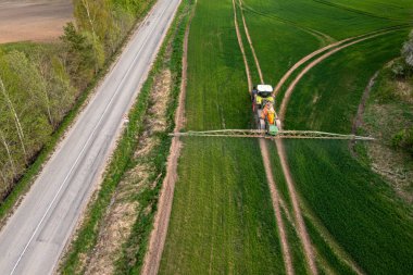 Traktörün yukarıdan aşağı görüntüsü kimyasalları büyük yeşil alana püskürtüyor, tarım konsepti