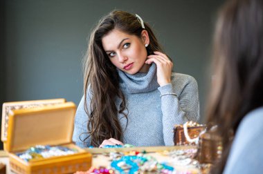 Aynada farklı takıları seçen ve deneyen bir kadının yansıması, yumuşak odak, yakın plan