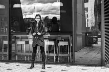 Finans bölgesinde cam kaplı bir binanın yanında zarif giyimli bir iş kadınının portresi.