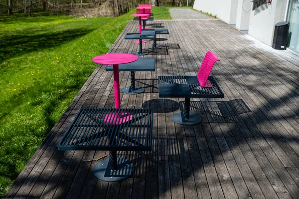 Güneşli bir günde terasta renkli metal banklar ve masalar