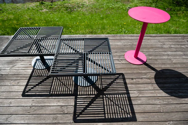 Güneşli bir günde terasta renkli metal banklar ve masalar