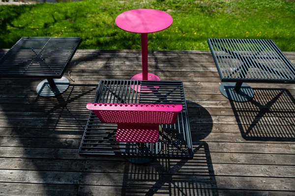 Güneşli bir günde terasta renkli metal banklar ve masalar