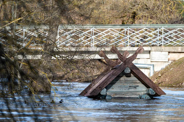 to the roof of a bird house flooded in spring floods - a feeder on the Berze River in Dobele, Latvia